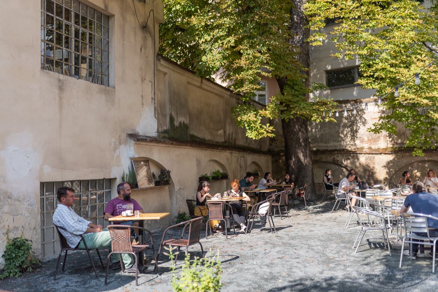 Zahrádka Spolku — stoly pod kaštanem u zdi klášterní zahrady